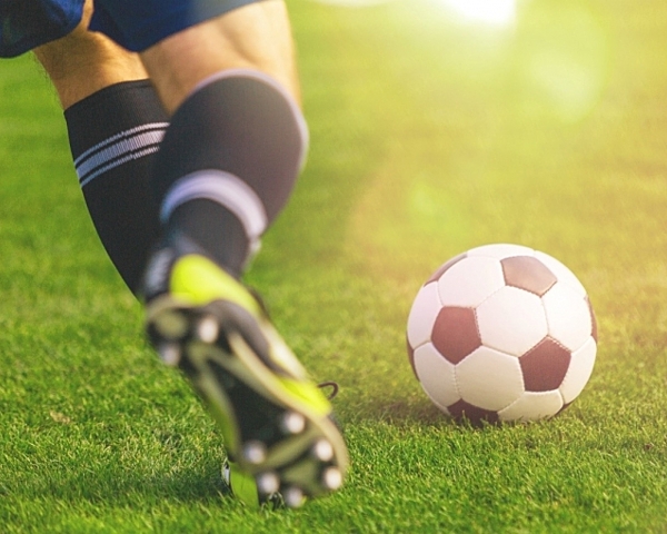 man in cleats kicking soccer ball 